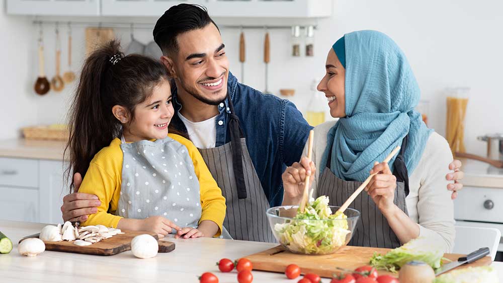 family smiling making a salad together