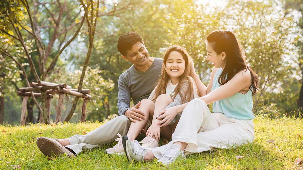 family sitting together in grass smiling